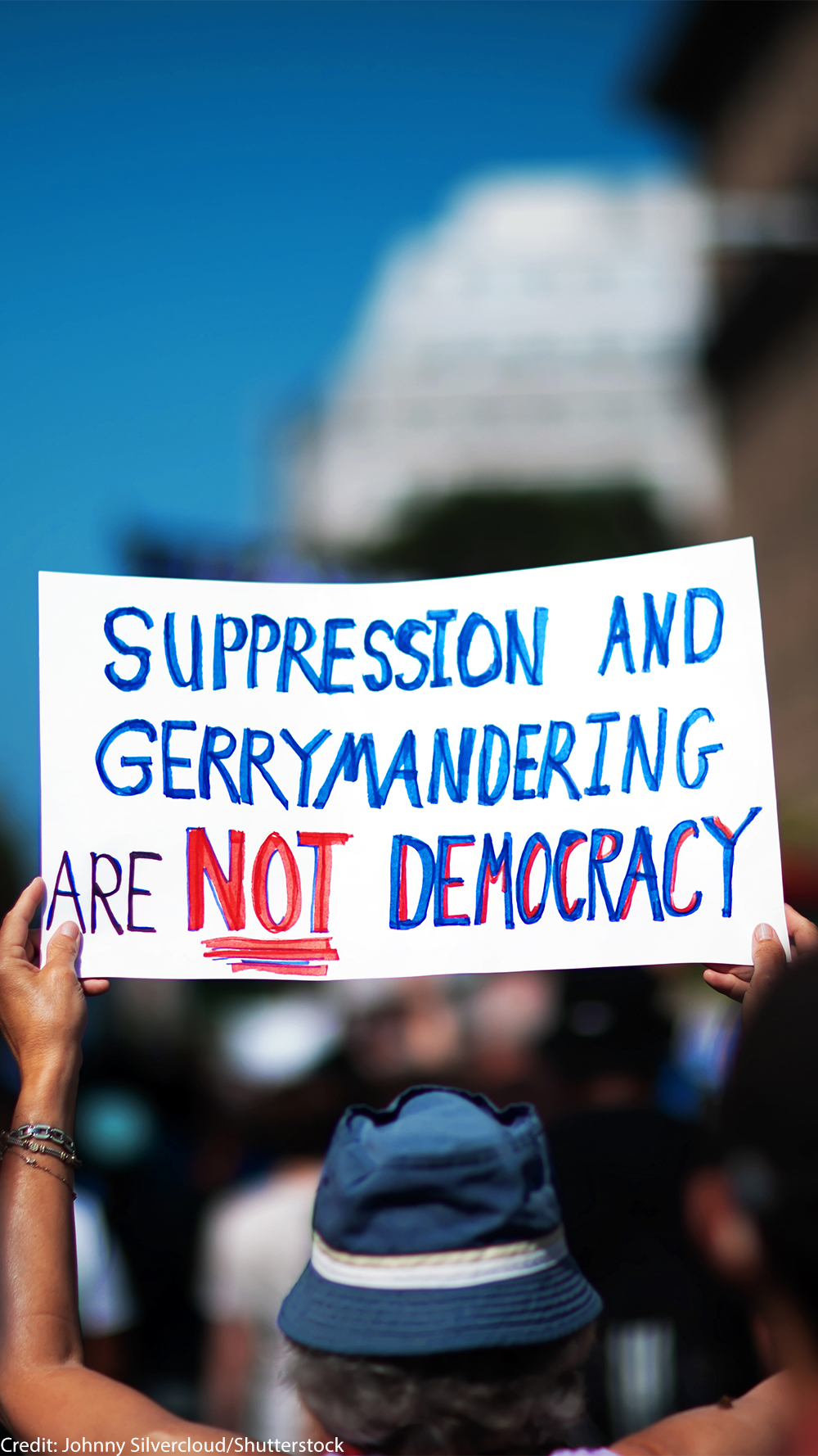 A demonstrator at the March On for Voting Rights in Washington D.C. holds up a sign reading "Suppression and Gerrymandering are Not Democracy".